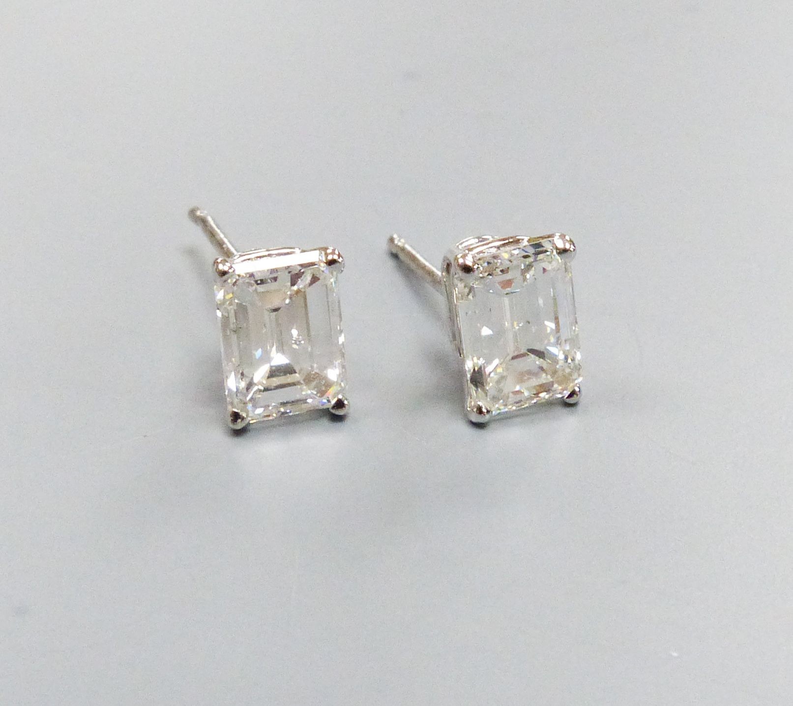 A modern pair of white metal and solitaire emerald cut diamond set ear studs, gross weight 1.1 grams